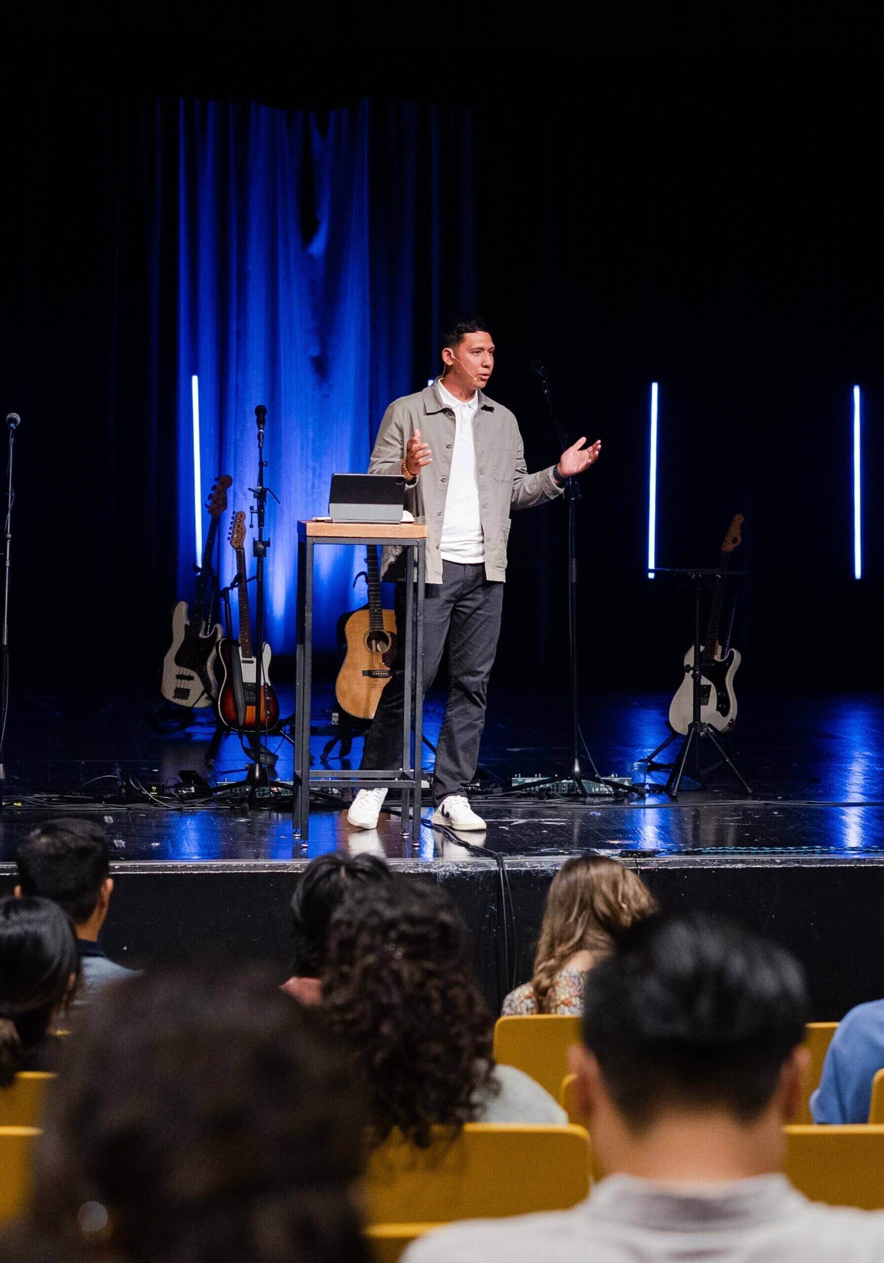 A pastor preaching on stage in front of an audience